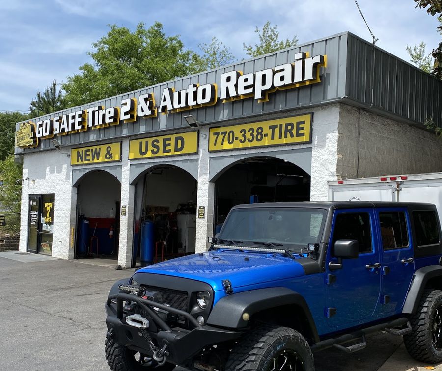 Go Safe Tire 2 shop exterior with yellow NEW & USED signage and open garage bays